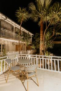阿莫利亚尼岛TRINITY THE HOTEL的棕榈树阳台的桌椅