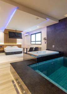 阿雷格里港Drops Motel POA Zona Sul的一间带游泳池、一张床和一个浴缸的浴室