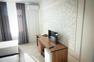 奇姆肯特Hotel Borjomi的酒店客房设有一张床和一张书桌上的电视