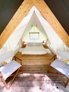 OplotnicaGlamping Tent Water Village Rogla的帐篷内的房间,配有一张床和两把椅子