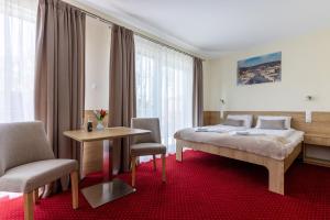 索波特KIWI Sopot Apartments的酒店客房带一张床、一张桌子和椅子