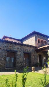 卡塞雷斯Casa rural Suerte de los Mozos的前面有草地的石头房子