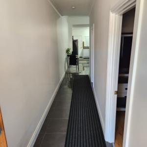 布罗肯希尔City Villa 39 Blende st Broken Hill NSW 2880的走廊设有白色墙壁和黑色瓷砖地板