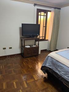 科恰班巴HABITACIONES PRIVADAS NOVILLO的一间卧室配有一张床和一张桌子上的电视