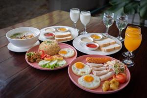 曼谷Gate43 Garden Villa的一张木桌,上面放有早餐食品和饮料盘
