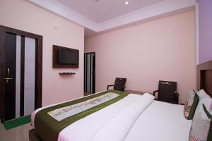 达兰萨拉OYO Hotel Chandni的卧室配有一张床,墙上配有电视。