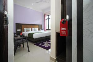 达兰萨拉OYO Hotel Chandni的一间房间,配有一张床和一个红色标志的门