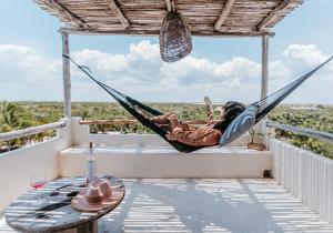 埃尔库约LunArena Boutique Beach Hotel Yucatan Mexico的躺在阳台上吊床上的女人