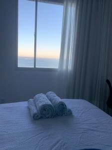 维拉维尔哈Apartamento Renovado na beira da Praia的一间卧室配有一张带毛巾的床,设有窗户