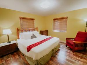 TerrebonneCrooked River Ranch Cabins的一间卧室配有一张大床和一张红色椅子