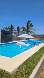 Celestino GascaTres Velas Surf的一个带遮阳伞和充气式游泳池