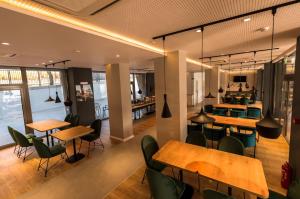 奥尔绍瓦Hotel Arka的餐厅设有木桌和绿色椅子