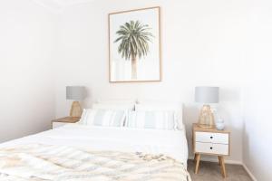 金斯克里福Kingscliff Paradise with Ocean Views的卧室配有白色的床,墙上挂着棕榈树照片