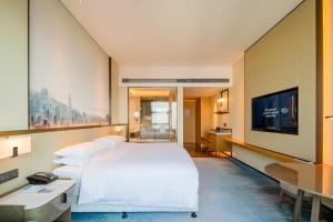 武汉武汉江夏联投福朋喜来登酒店的一间酒店客房,配有一张大床和一台平面电视