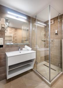 久洛Hunguest Hotel Gyula的一间带水槽和玻璃淋浴的浴室