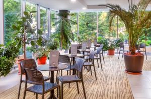 久洛Hunguest Hotel Gyula的一间设有桌椅的餐厅,种植了植物