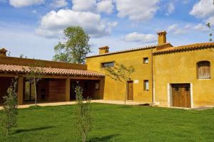 赫罗纳Mas Garriga Turisme Rural的一座大型黄色房子,设有绿色庭院