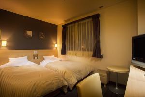 富士吉田市Hotel Fuji Tatsugaoka的酒店客房设有两张床和电视。