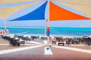马特鲁港Triumph White Sands Hotel的海滩上的一组椅子和一把遮阳伞