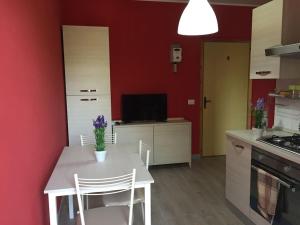 科帕内罗Bilo Copanello Imminens Mari的厨房配有白色的桌椅和红色的墙壁