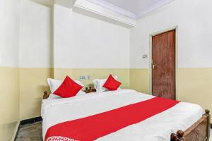 瓦朗加尔OYO Suraj Residency的一间卧室配有一张带红色枕头的大床
