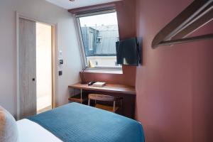 巴黎Hôtel Maxim Quartier Latin的一间卧室配有一张床和一张带窗户的书桌