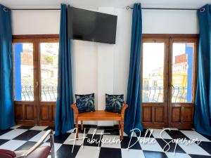 多列毛利诺斯Micaela Charming Hostal的一间设有蓝色窗帘、椅子和电视的客房