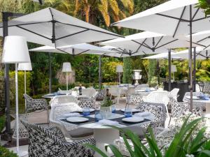 蒙特卡罗Hôtel Métropole Monte-Carlo - Deux restaurants étoilés的庭院配有白色的桌椅和遮阳伞。