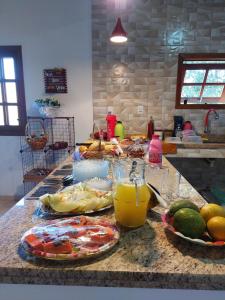帕蒂杜阿尔费里斯Pousada e Pesque e Pague Vista Alegre的厨房柜台,配有食物盘和橙汁杯