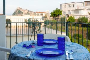 伊斯基亚Villa dei Sogni - Aparthotel Ischia Ponte的阳台上配有带盘子和蓝色玻璃杯的蓝色桌子