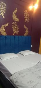 马图拉Manavi Home Stay的一张带蓝色床头板的床,墙上挂着金色龙