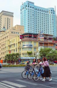 胡志明市Sheraton Saigon Grand Opera Hotel的三个女孩骑着自行车沿着城市的街道骑着