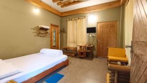Uttar SimlabariSDD Bamboo Village Resort的一间卧室配有一张床、一张桌子和一把椅子