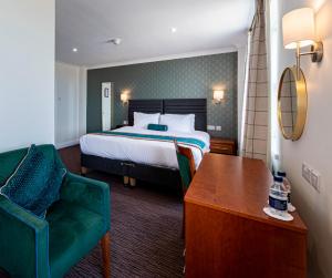 普利斯坦丁海滩酒店的酒店客房,配有一张床和一把绿色椅子