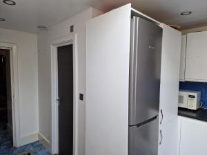 达格纳姆Studio Flat with kitchen and toilet included的一间厨房内的不锈钢冰箱,厨房内有白色的橱柜