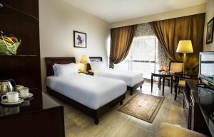卢克索Pyramisa Hotel Luxor的酒店客房设有两张床、一张桌子和一台电视。