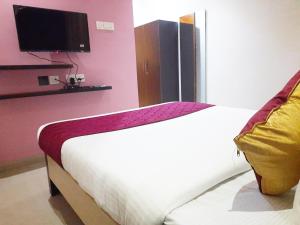 坦贾武尔Hotel Abedrooms- Budget stay Thanjavur的一间卧室配有一张床,墙上配有电视