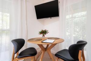 比奇沃斯Beechworth House的一张桌子,有四把椅子,墙上有一台电视