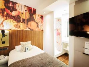 里昂里昂中心共和广场美居酒店的一间卧室配有一张床和一台平面电视