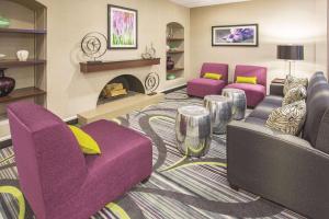萨克拉门托Howard Johnson by Wyndham Sacramento Downtown的客厅配有紫色椅子和壁炉