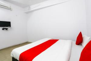 加济阿巴德OYO Hindon Residency的一间配有电视的客房内的一张红色和白色的床