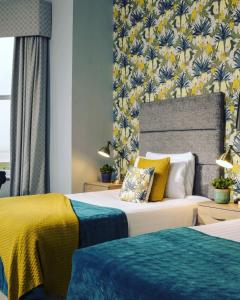 莱瑟姆-圣安妮Clifton Arms Hotel的一间卧室设有两张黄色和蓝色的床