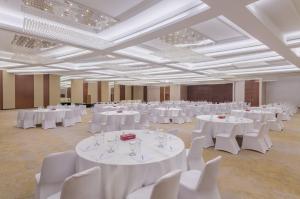 马斯喀特IntercityHotel Muscat的大房间设有白色的桌子和白色的椅子