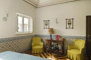 梅利迪什Vermelho Melides的一间卧室配有两张黄色椅子、一张桌子和一张床