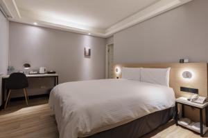 台北Hubhotel Benqiao Inn Far Eastern Branch的卧室配有一张白色大床和一张书桌