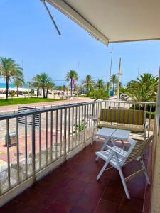 甘迪亚海滩Apartamento TalaMar Gandia Playa的阳台配有桌椅,享有海滩美景。