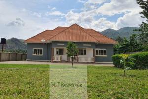 卡塞斯BLT Residence - Kasese A serene and tranquil home的一座红色屋顶和绿色庭院的房子