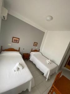 Aldea QuintanaHostal Carlos III的配有2张床的客房内配有白色床单和毛巾