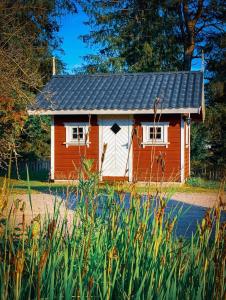 希恩Koselig hytte langs elven的草上的一个红色和白色的小房子