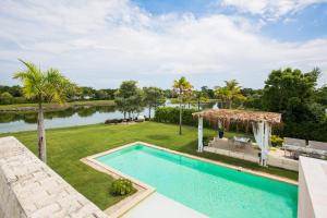 蓬塔卡纳Tranquil Lakefront 5-Bedroom Villa with Cook, Maid, Golf Cart, and Beach Access in Punta Cana的游泳池和带湖泊的后院的图片